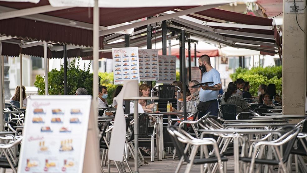 Un camarero atiende una mesa en la terraza de una cafetería