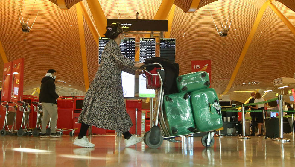 Una mujer camina con varias maletas en un carro en la terminal T4 del Aeropuerto Adolfo Suárez Madrid-Barajas
