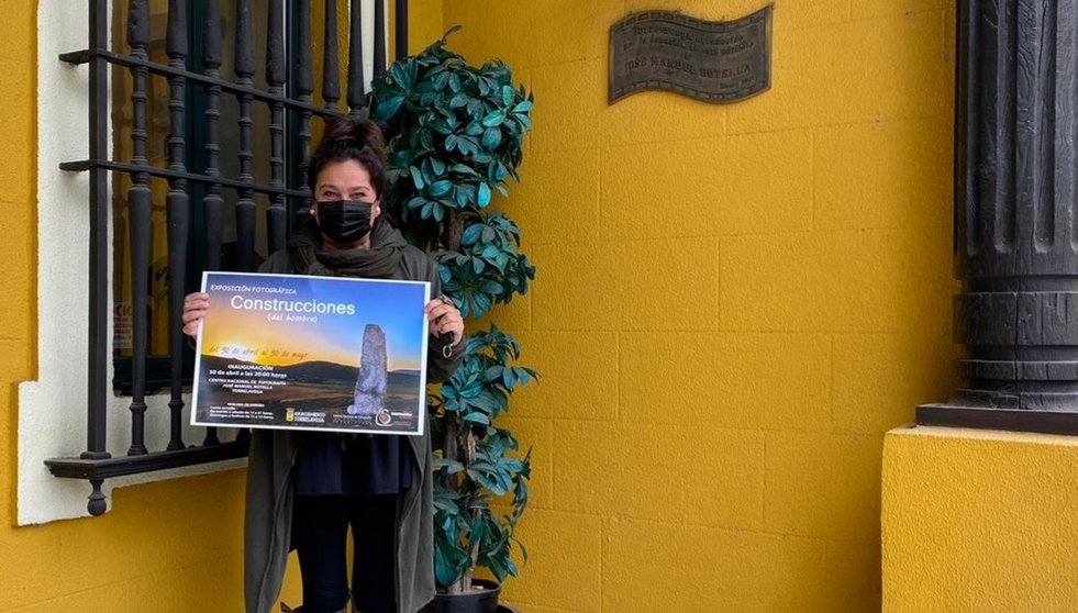La concejala de Cultura de Torrelavega, Esther Velez, con el cartel de la exposición sobre las construcciones del hombre