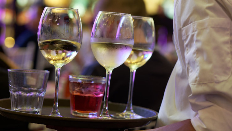 Un camarero sostiene una bandeja con copas en un bar