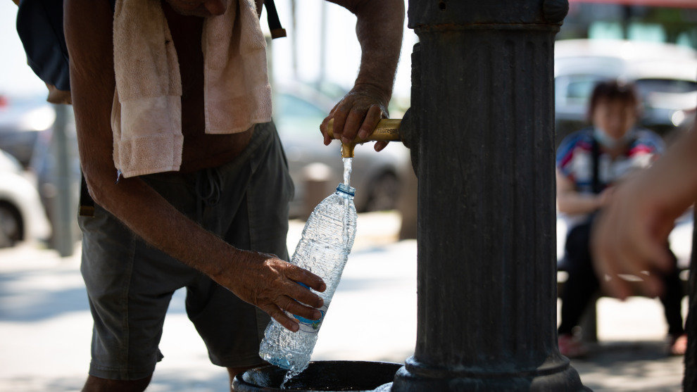 Un hombre rellena una botella de agua en una fuente en el parque