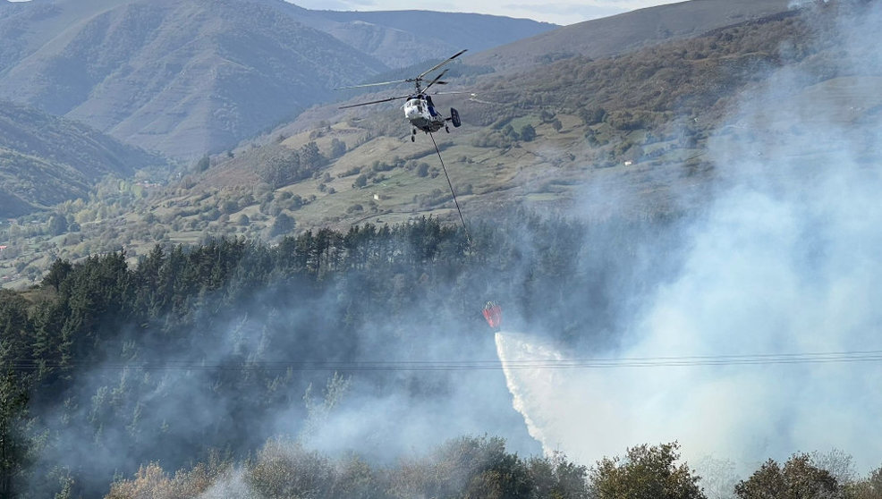Un helicóptero trata de apagar el incendio forestal en Arenas de Iguña