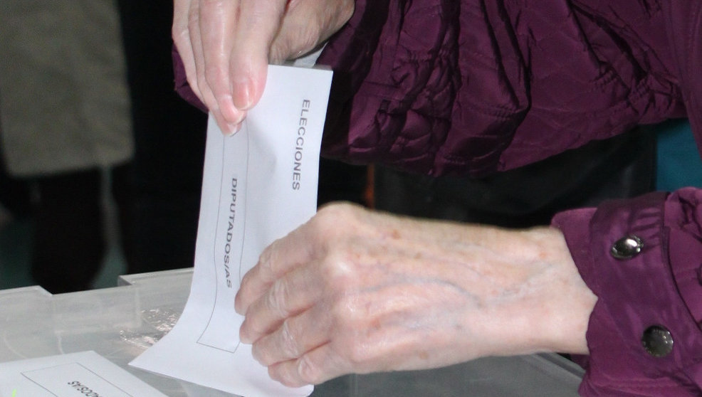 Una mujer introduciendo su voto en las urnas