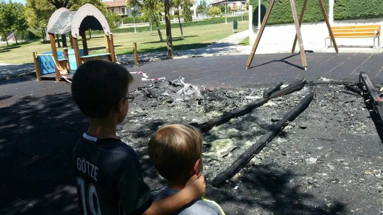 Dos ni&ntilde;os contemplan el parque infantil de Zizur Mayor calcinado tras un acto de vandalismo