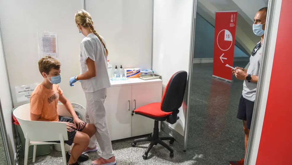 Una sanitaria vacuna a un adolescente con la primera dosis de la vacuna Moderna