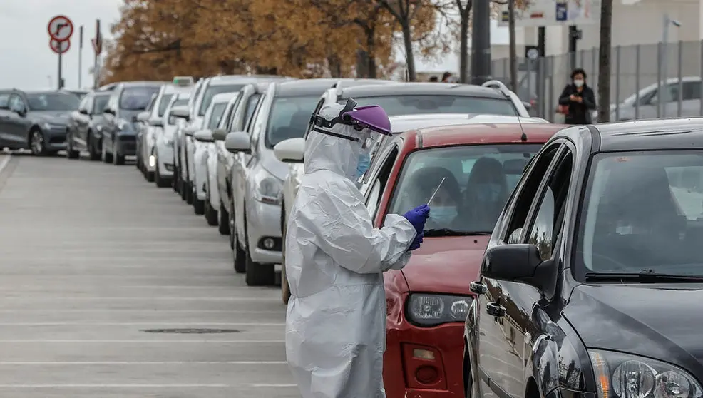 Un sanitario realiza una prueba PCR a una persona desde su vehículo para la detección del coronavirus