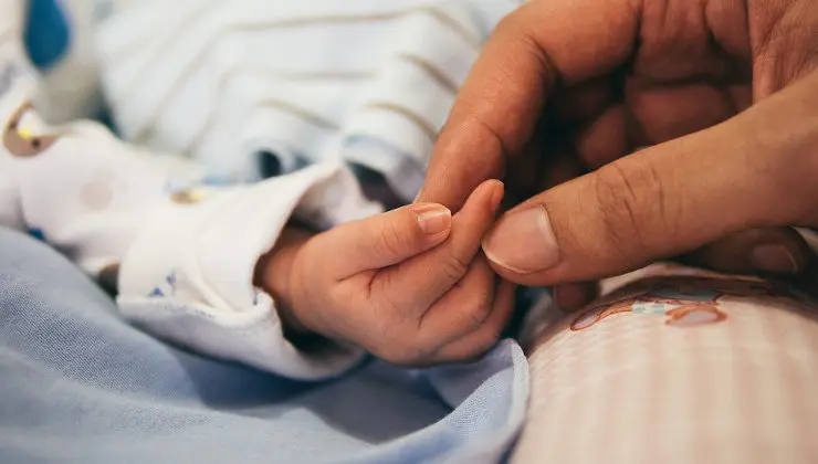 Mano de una madre sujetando la de su bebé