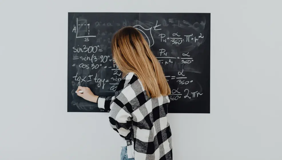 Una mujer escribe en una pizarra un problema de matemáticas
