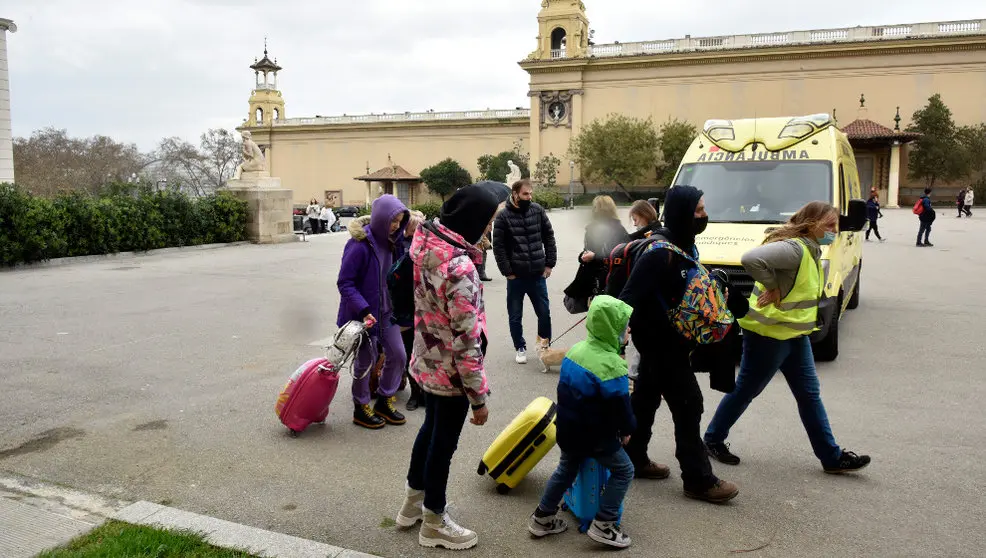 Varios refugiados y una traductora junto a una ambulancia