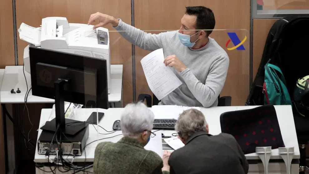 Un trabajador de la Oficina de la Agencia Tributaria atiende a dos personas