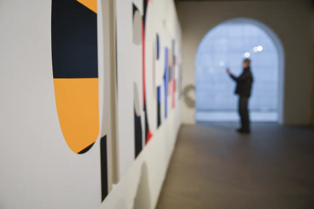 Una persona contempla varias obras de dise&ntilde;o gr&aacute;fico y tipogr&aacute;fico