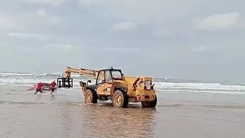 Un veh&iacute;culo pesado saca del mar, en la playa de Oyambre, al turismo que qued&oacute; encallado