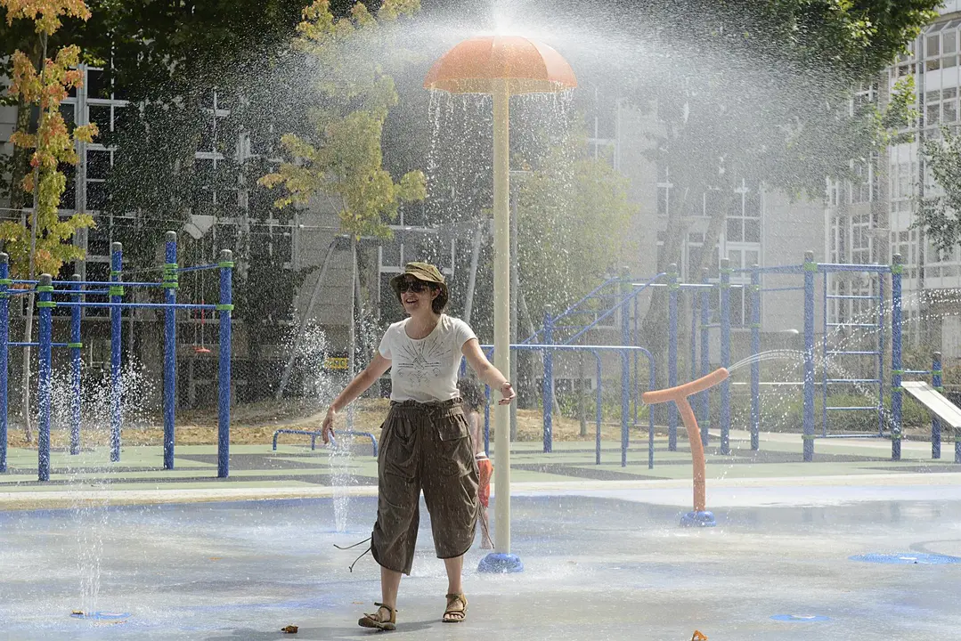 Una mujer se refresca en unos chorros de un parque durante un día de la segunda ola de calor de verano en España, a 14 de julio de 2022, en Ourense, Galicia