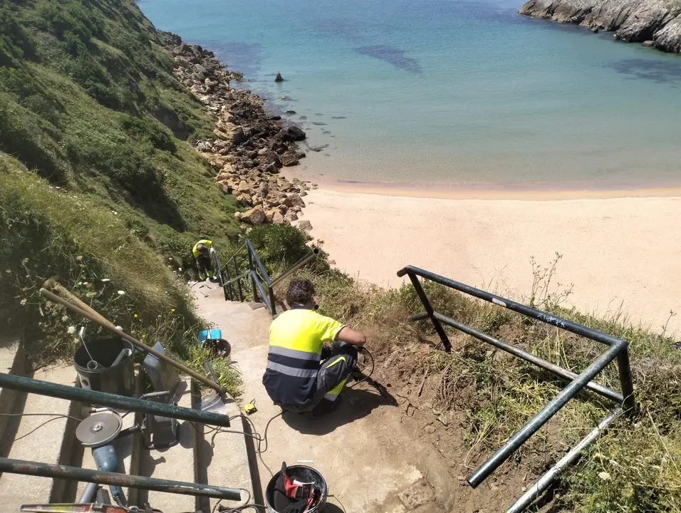 Personal de Piélagos repara la barandilla de acceso a la playa de Somocuevas tras la autorización de Costas 