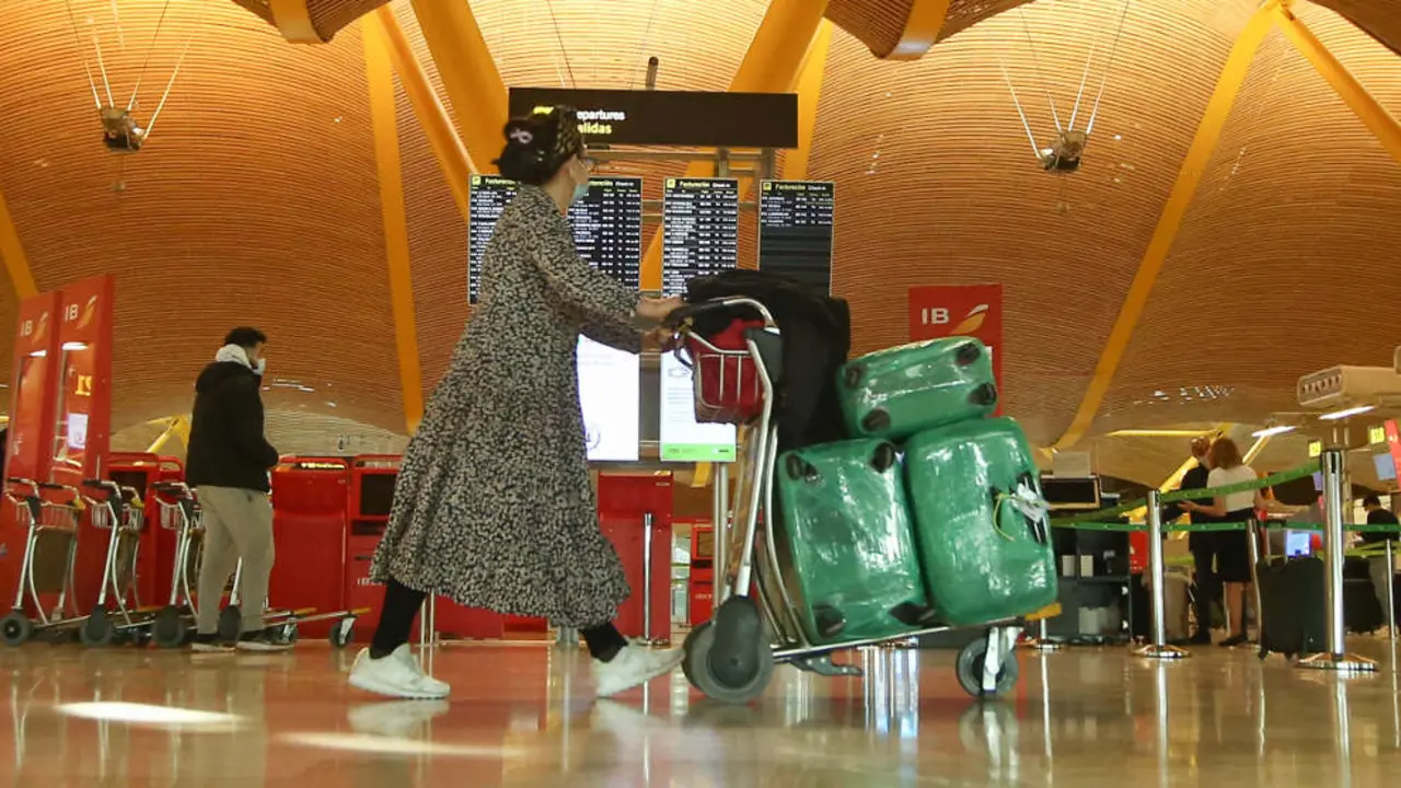 Una mujer camina con varias maletas en un carro en la terminal T4 del Aeropuerto Adolfo Suárez Madrid-Barajas