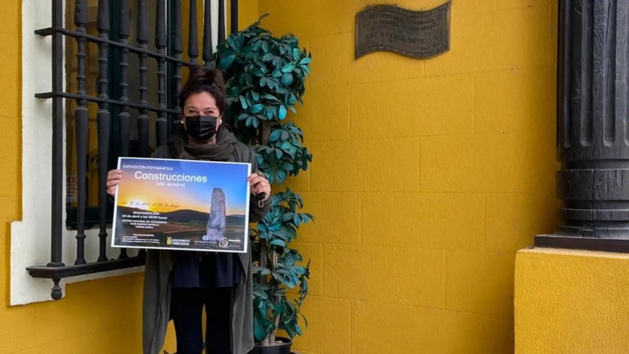 La concejala de Cultura de Torrelavega, Esther Velez, con el cartel de la exposici&oacute;n sobre las construcciones del hombre