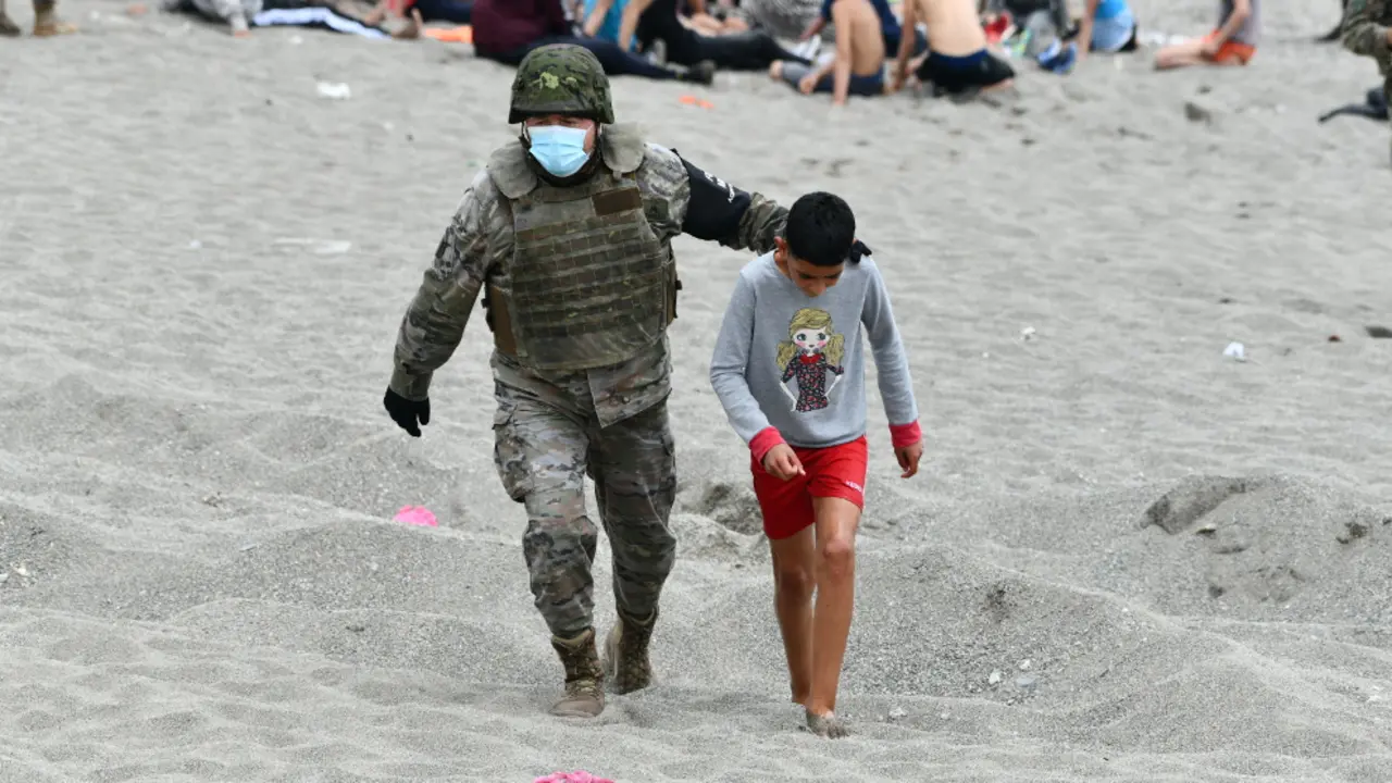 Un militar del ej&eacute;rcito espa&ntilde;ol acompa&ntilde;a a un ni&ntilde;o en una jornada marcada por las devoluciones en caliente que est&aacute;n efectuando a los migrantes que han entrado en Ceuta procedente de Marruecos, a 18 de mayo de 2021, en Ceuta | Foto: Antonio Sempere / Europa Press