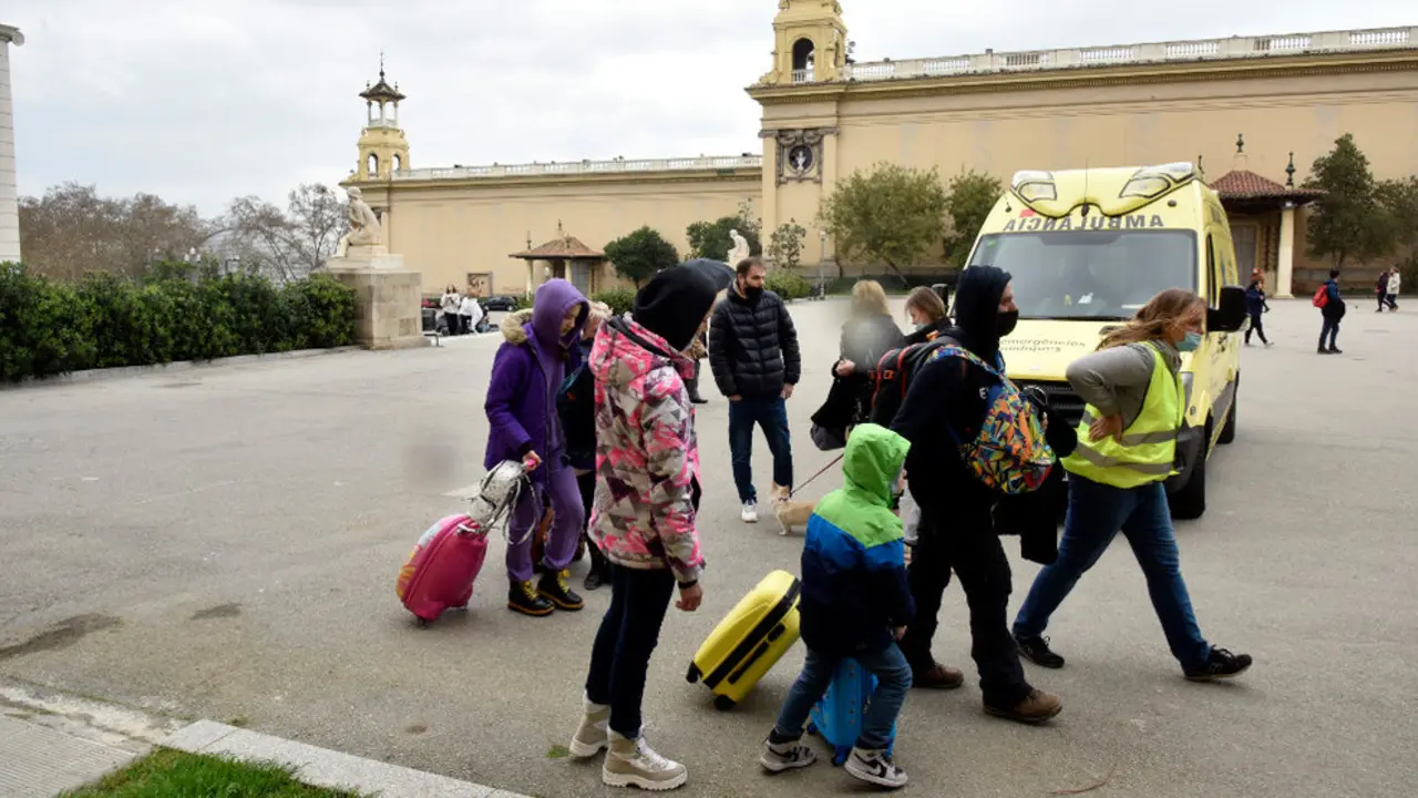 Varios refugiados y una traductora junto a una ambulancia
