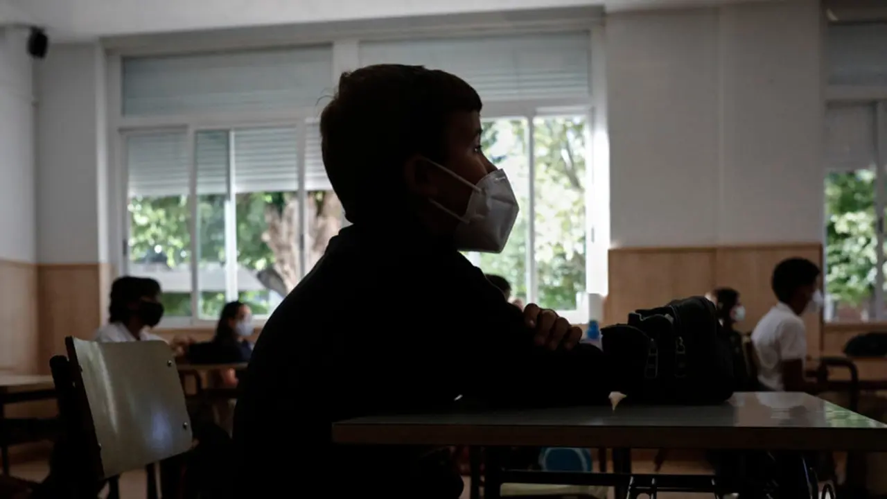Un niño con mascarilla en un aula