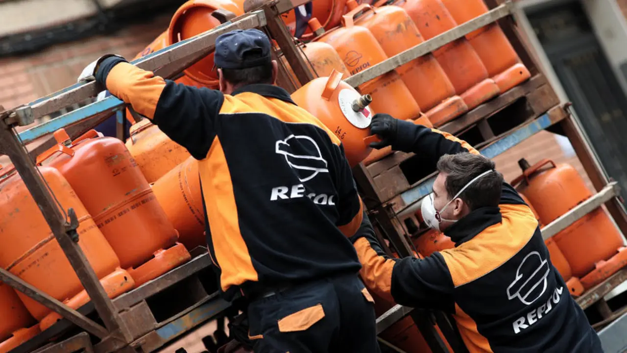 Dos butaneros descargan bombonas para su reparto