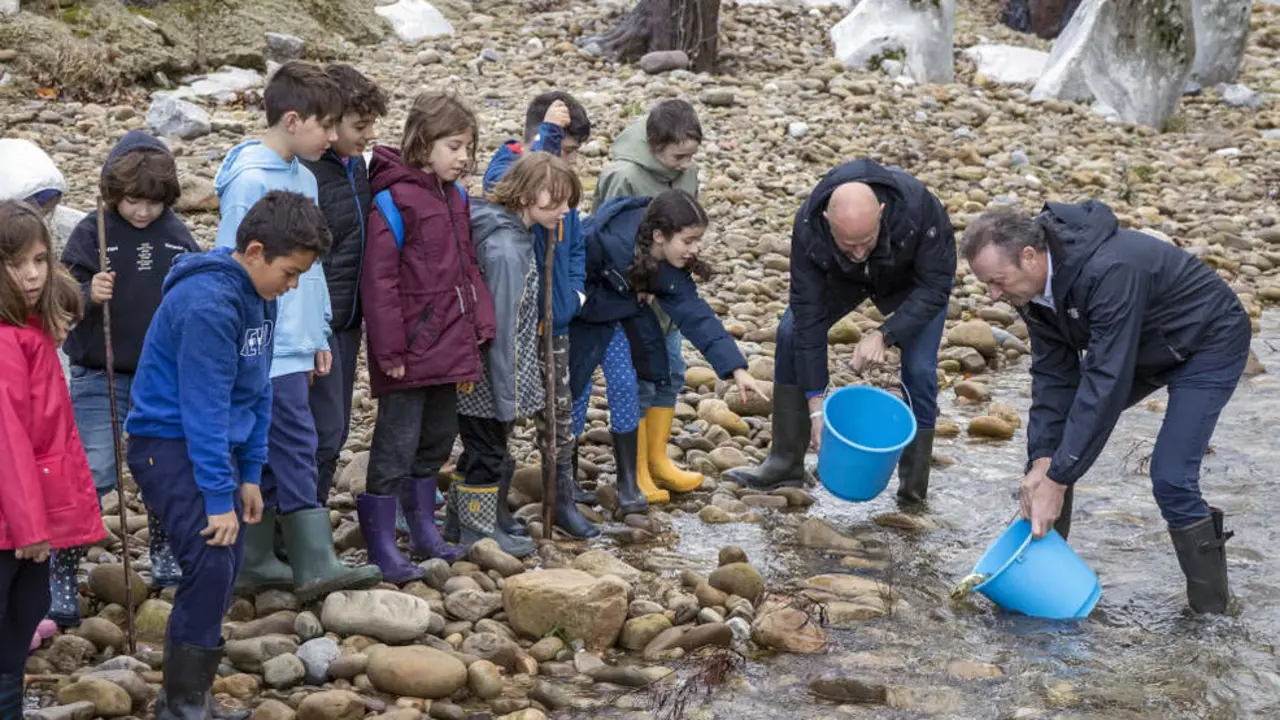 El consejero de Pesca, Guillermo Blanco, participa junto a un grupo de alumnos en la suelta de alevines de salmón en el Pas