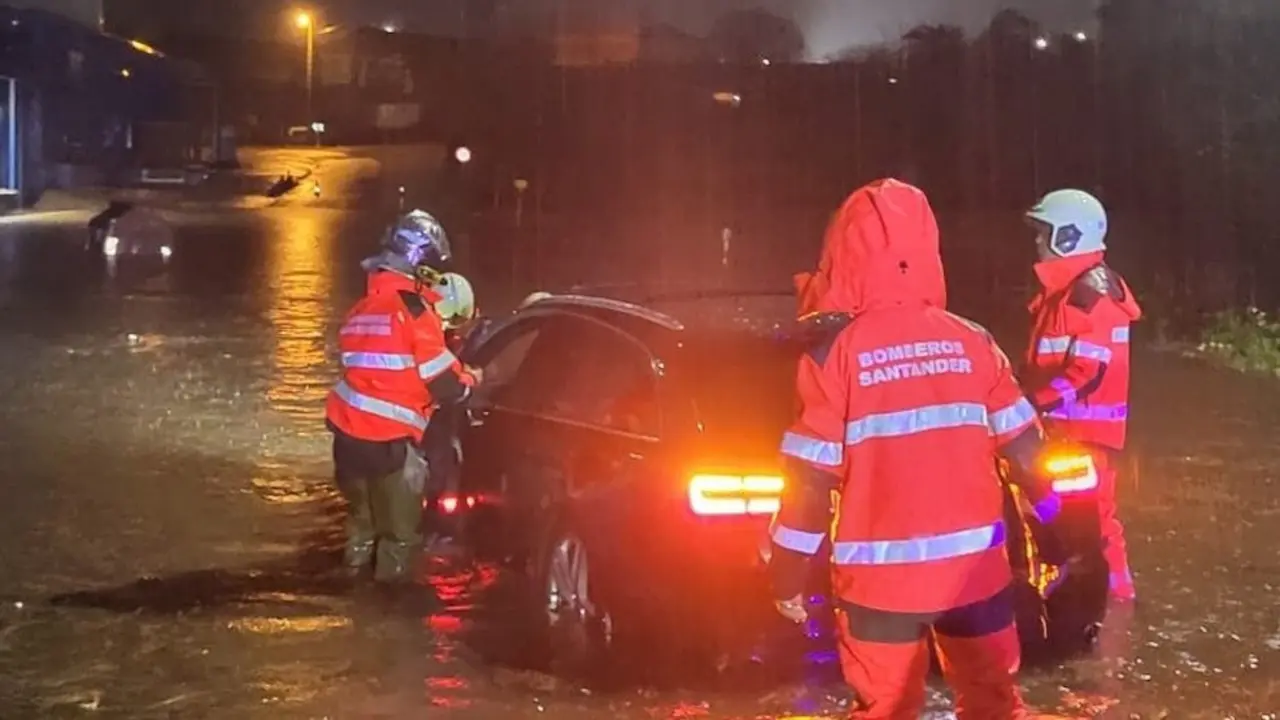 Los bomberos atendiendo un vehículo atrapado por la lluvia