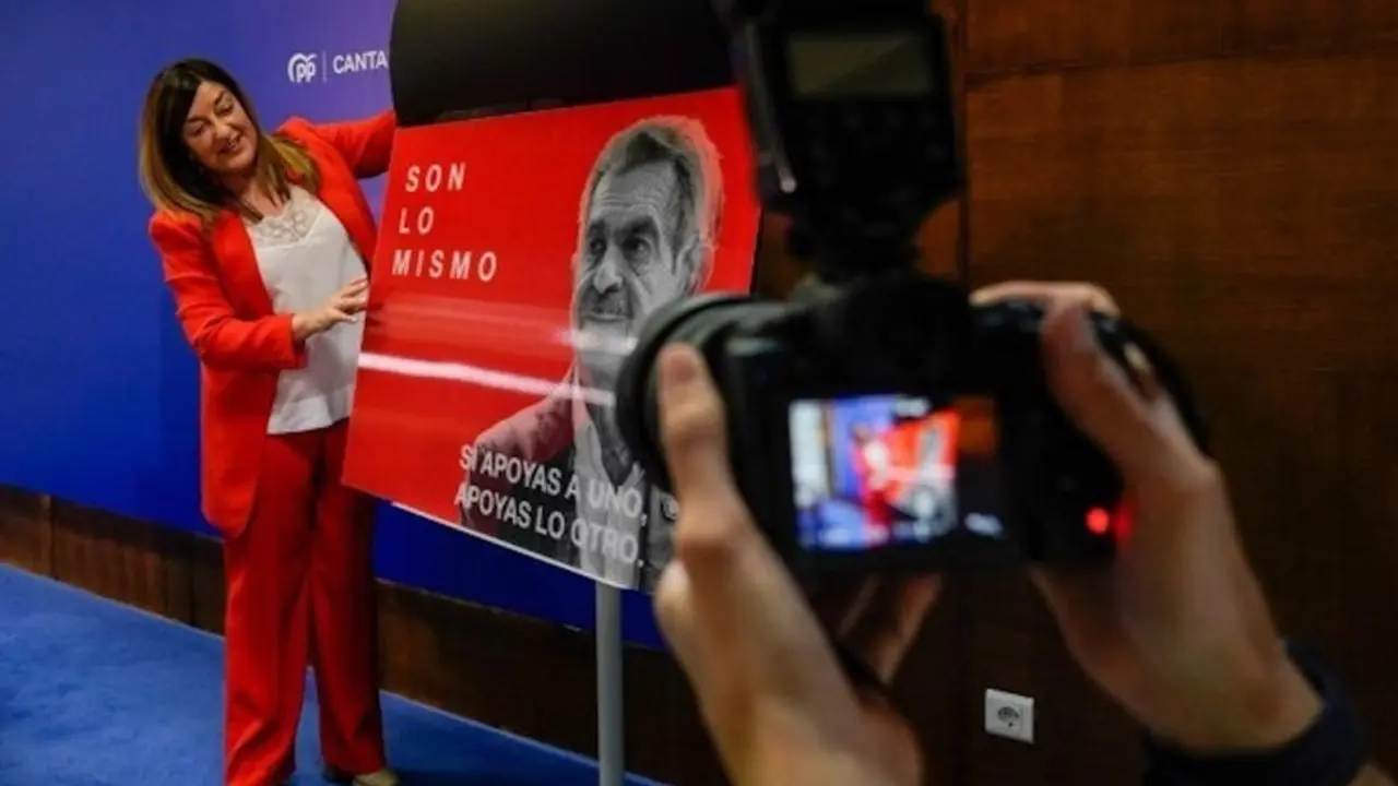 La presidenta del PP de Cantabria, María José Sáenz de Buruaga, mostrando el cartel con las caras de Revilla y Sánchez
