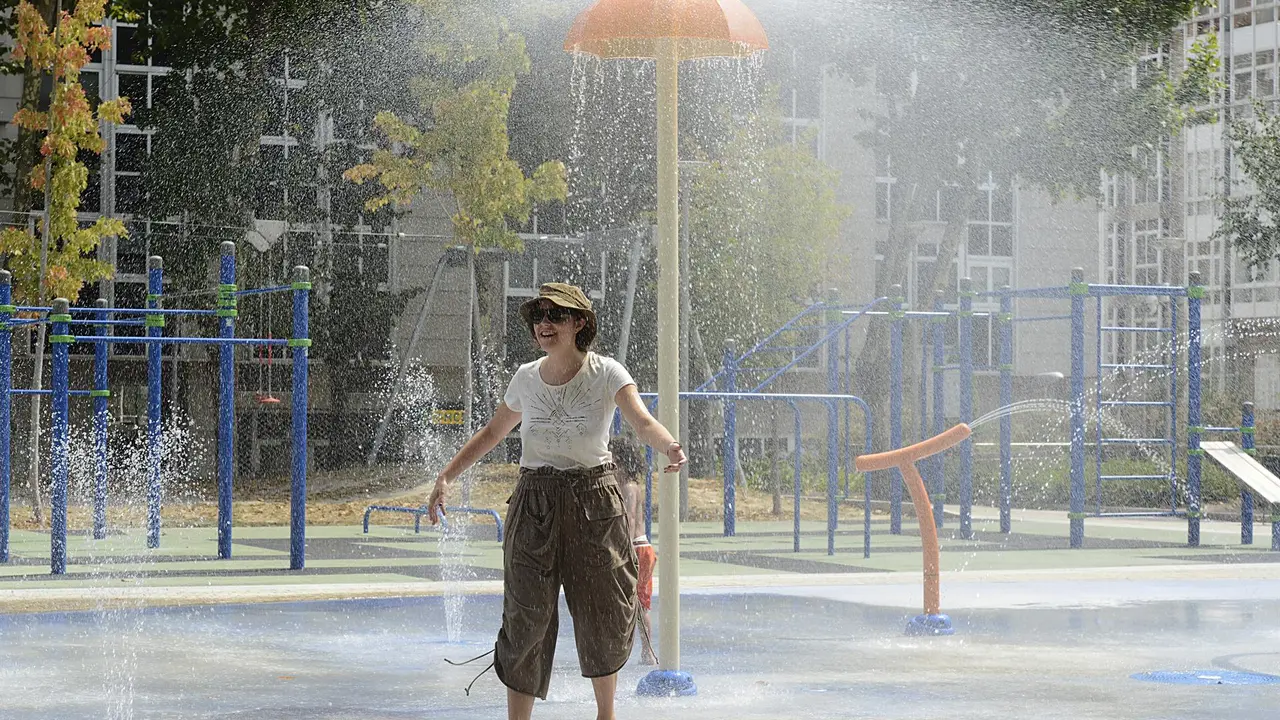 Una mujer se refresca en unos chorros de un parque durante un día de la segunda ola de calor de verano en España, a 14 de julio de 2022, en Ourense, Galicia